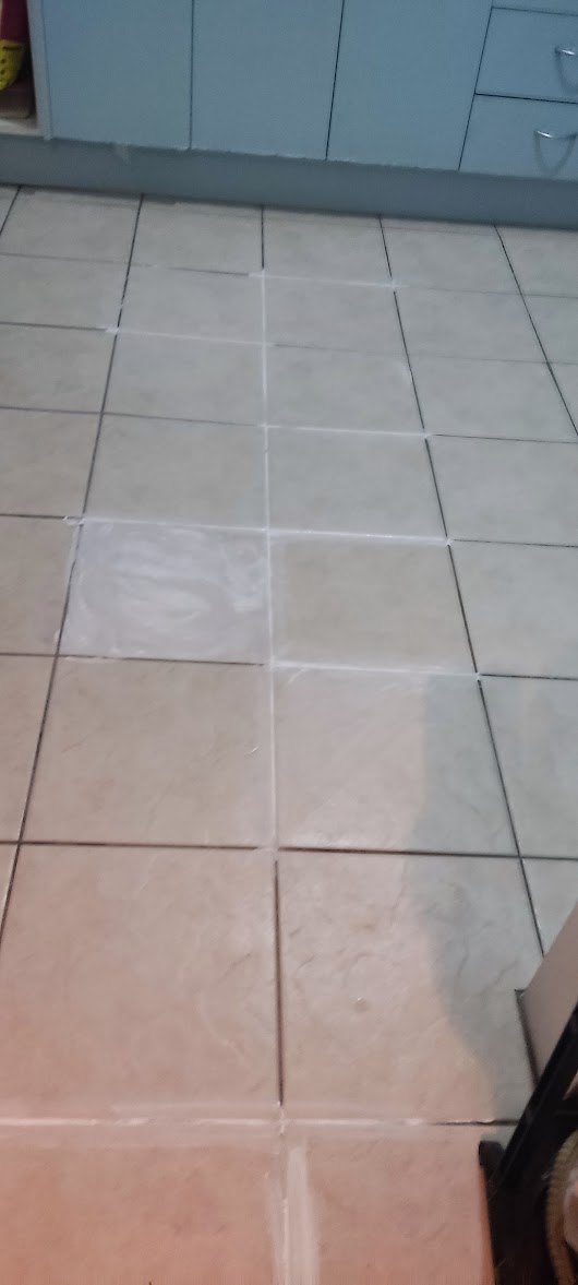 Kitchen floor before restoration, showing dark and uneven grout lines