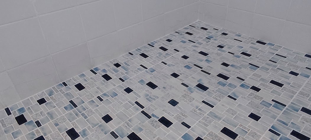 Finished light grout restoration across a blue mosaic shower floor